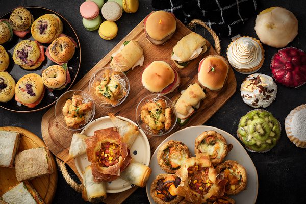 Mesa con productos de catering: tartines, tartas dulces, sandwiches, chicken fingers y macarrons